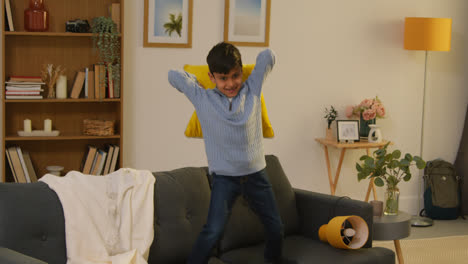 Disruptive-Young-Boy-Behaving-Badly-At-Home-Jumping-On-Sofa-And-Throwing-Cushions-Around-Lounge-4
